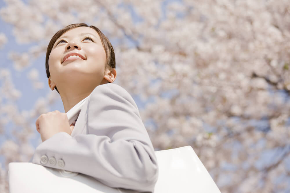 桜の木の下で微笑む新社会人