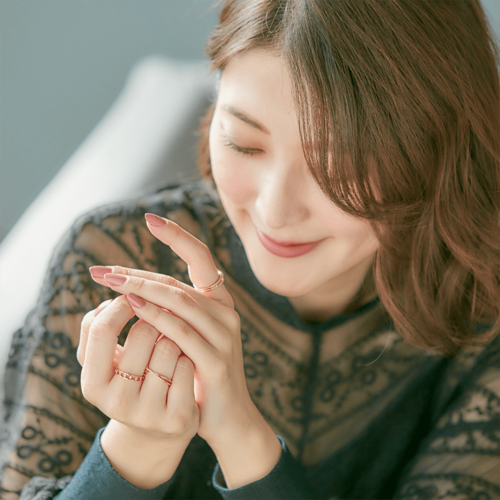 ピンクのネイルをした手に4℃の指輪を複数使い