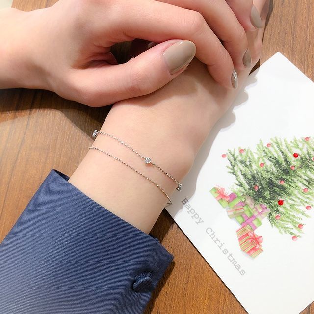 メッセージカードとブレスレットを身に着けた女性の手
