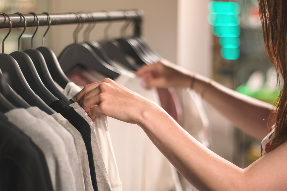 ハンガーラックから服を選ぶ女性